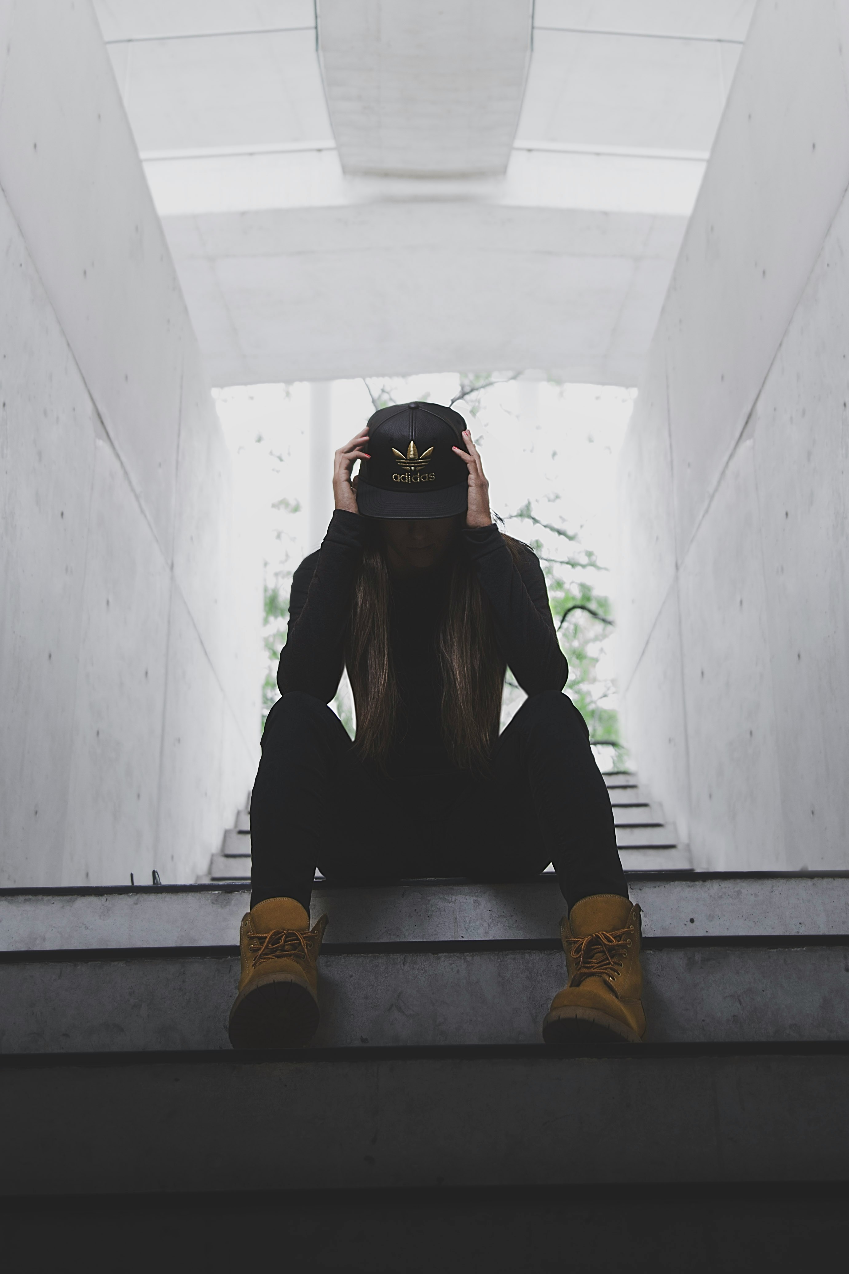 woman in black jacket and blue denim jeans sitting on concrete stairs